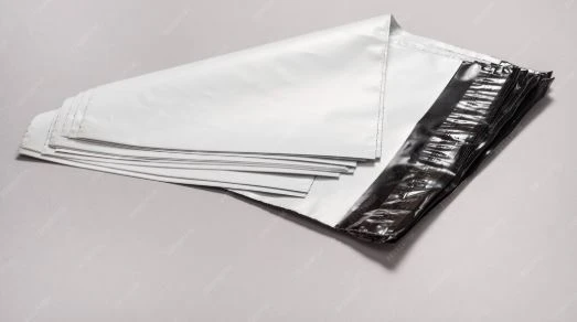 Sacos de lixo preto e branco empilhados, prontos para descarte ou coleta em uma área residencial ou comercial.